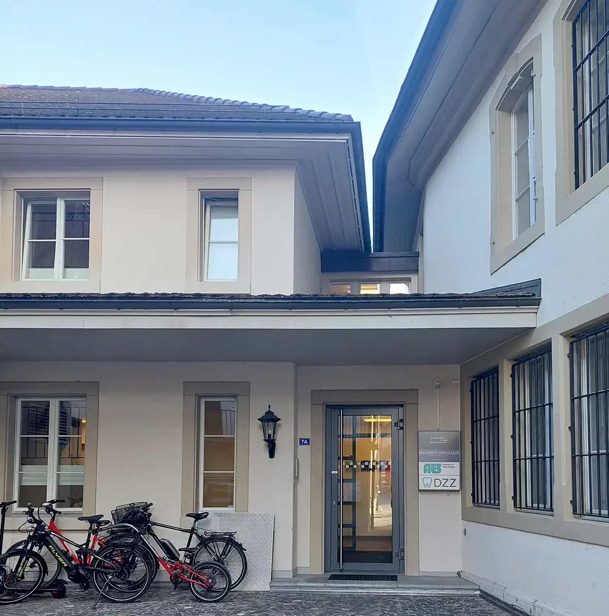 Image of a buliding in Switzeland with bikes off to the left of a door, with an AES sign on the right.