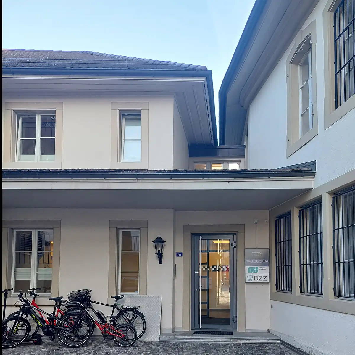 Image of a buliding in Switzeland with bikes off to the left of a door, with an AES sign on the right.